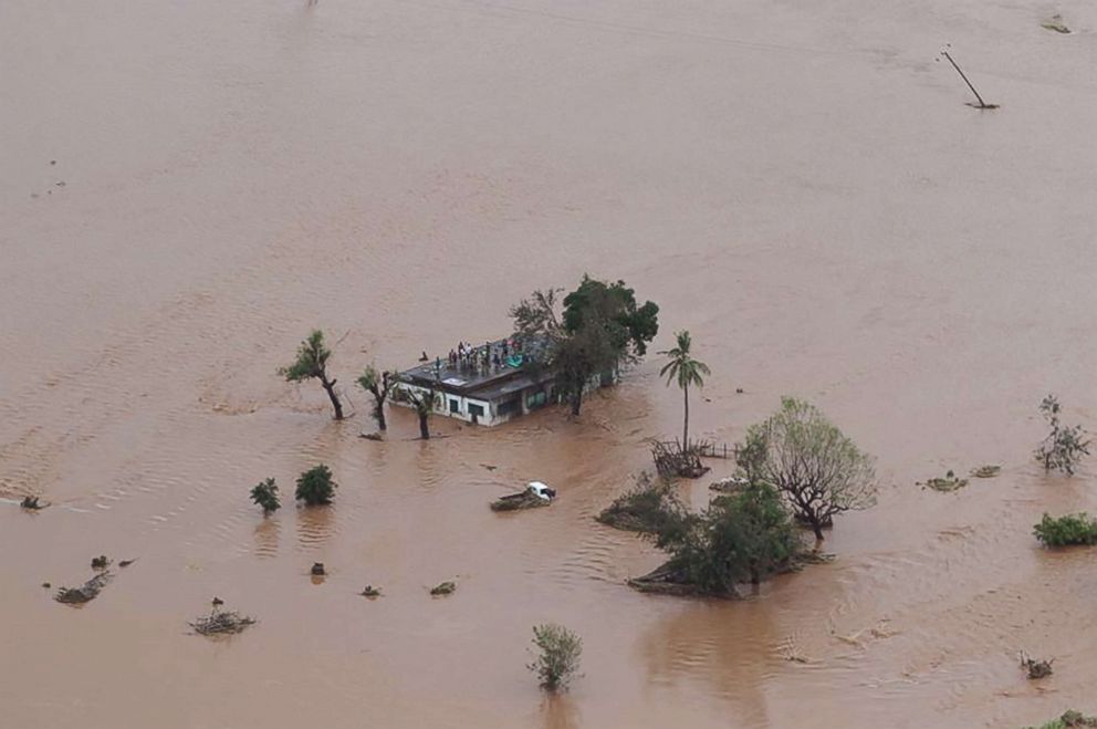 PHOTO: This handout picture taken and released, March 18, 2019, by the Mission Aviation Fellowship shows people on a roof surrounded by flooding in an area affected by Cyclone Idai in Beira.