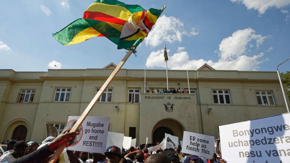 PHOTO: Protesters calling for the impeachment of President Robert Mugabe brandish a national flag as they demonstrate outside the parliament building in Harare, Zimbabwe, Nov. 21, 2017. 