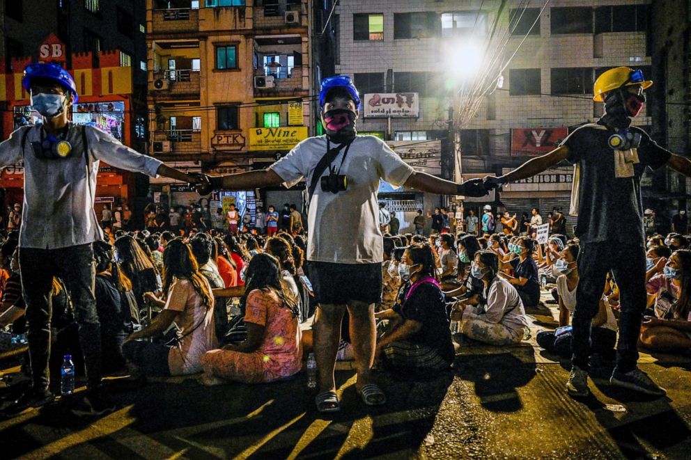 PHOTO: Protesters hold hands to keep watch during a night-time demonstration against the military coup in Yangon on March 13, 2021.