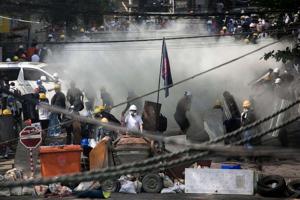 PHOTO: Protesters behind a barricade are enveloped by tear gas during a demonstration in Yangon, March 3, 2021.