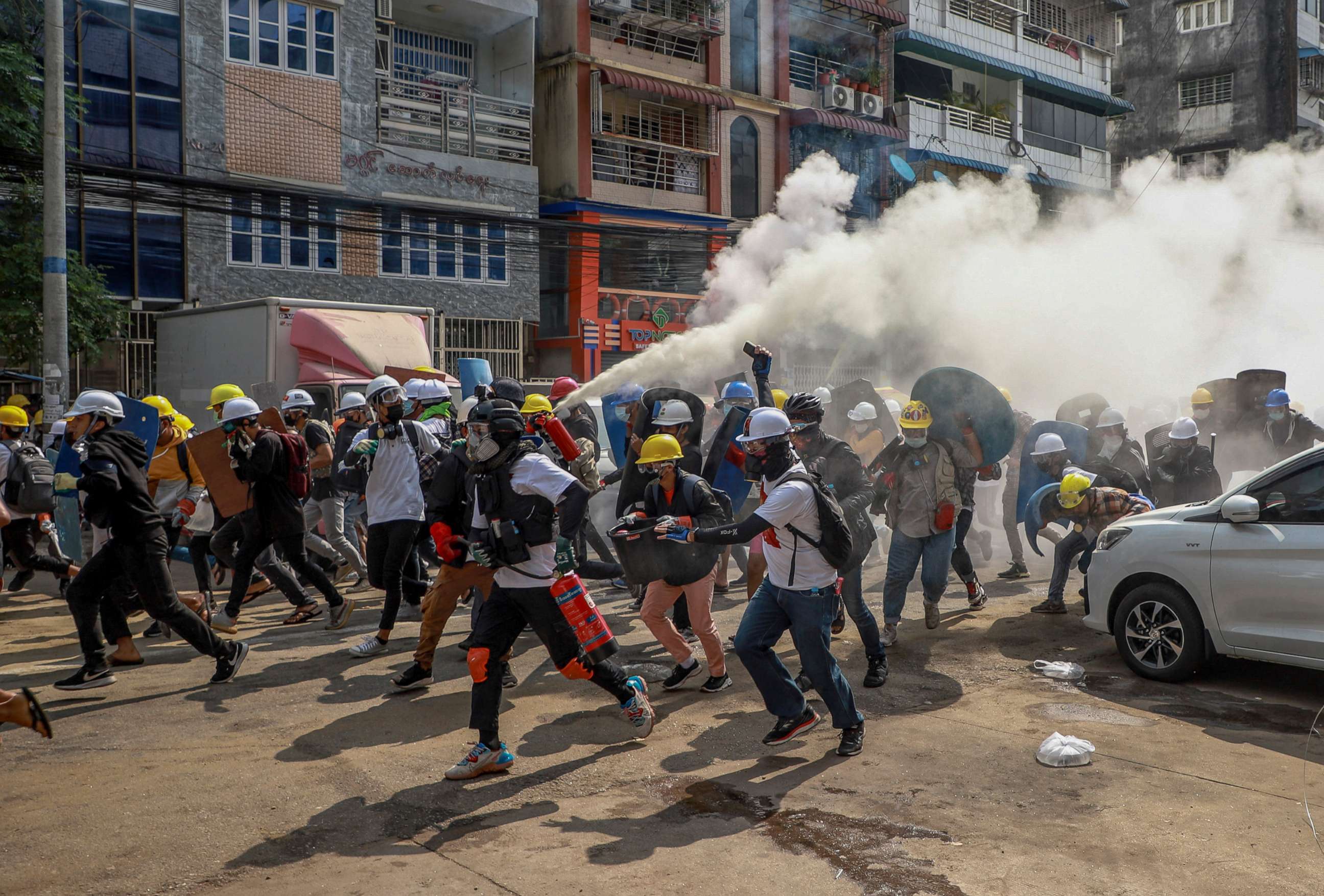 PHOTO: Protesters run as one of them discharges a fire extinguisher to counter the impact of tear gas fired by riot policemen in Yangon, Myanmar, March 3, 2021.