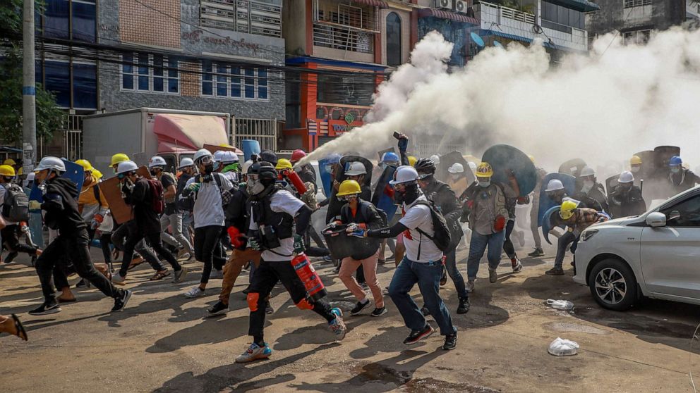 PHOTO: Protesters run as one of them discharges a fire extinguisher to counter the impact of tear gas fired by riot policemen in Yangon, Myanmar, March 3, 2021.