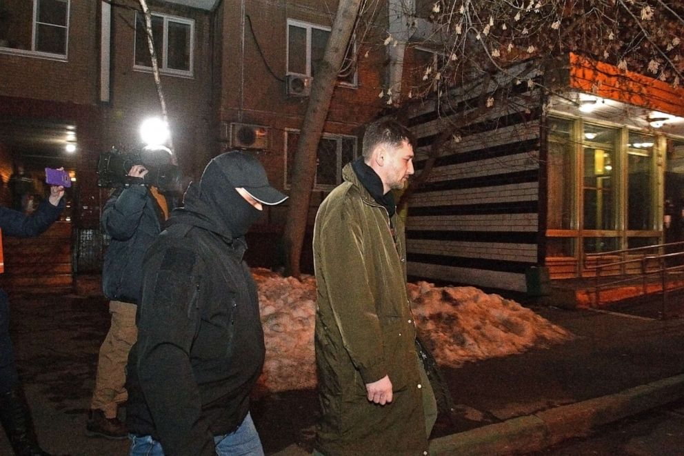 PHOTO: Oleg Navalny (right), accompanied by police officers, walks out after his brother Alexei Navalny's apartment was searched in connection to alleged violations of sanitary and epidemiological rules, on Jan. 27, 2021 in Moscow.  