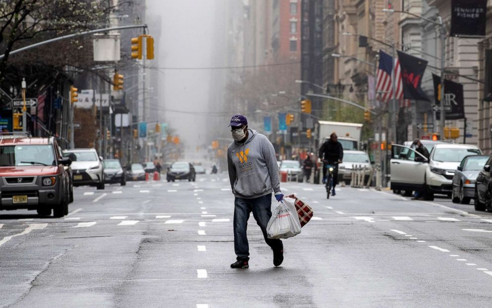 PHOTO: A man wearing a facial mask walks across the middle of 5th Avenue in New York City, March 29, 2020.
