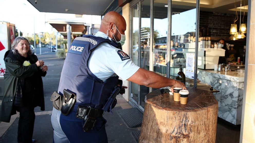 PHOTO: A police officer wearing a mask gets his morning coffee from The Store in Kohimarama as Auckland wakes to a return to level three lockdown, Aug. 13, 2020, in Auckland, New Zealand.