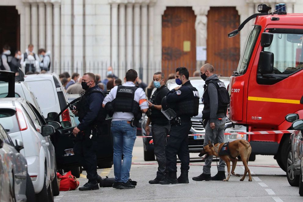 PHOTO: A police dog handler and officers search a car parked near the Basilica of Notre-Dame de Nice (background) after a knife attack in Nice on Oct. 29, 2020.