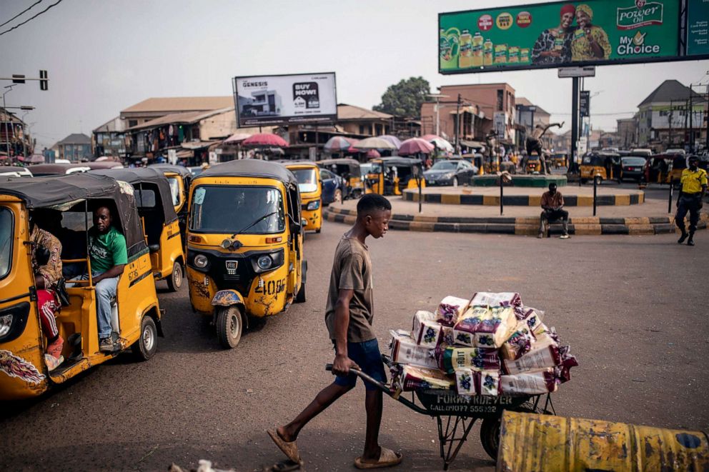 PHOTO: Tuk-tuks, or tricycles, carry customers in a local market as a vendor pushes a cart of goods in Anambra state, southeastern Nigeria, on Feb. 24, 2023.