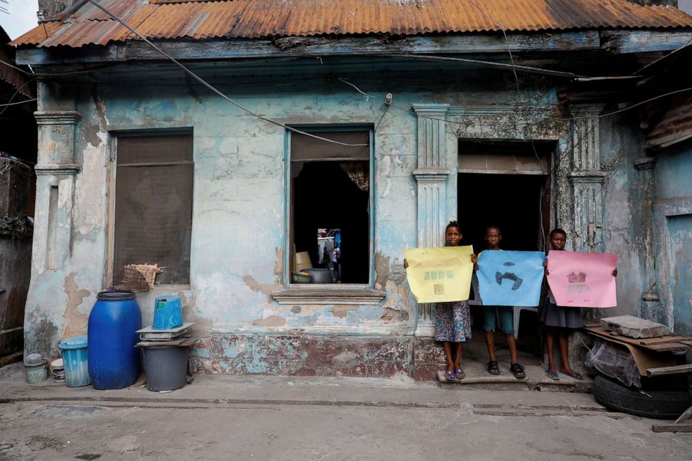 PHOTO: Sofiat Kolawole, 8, Olatunji Adebayo, 11, and Amira Akanbi 11, pose for a photograph while holding pictures that they drew during the coronavirus pandemic, as they stand in front of their house in Lagos, Nigeria, on April 18, 2020.