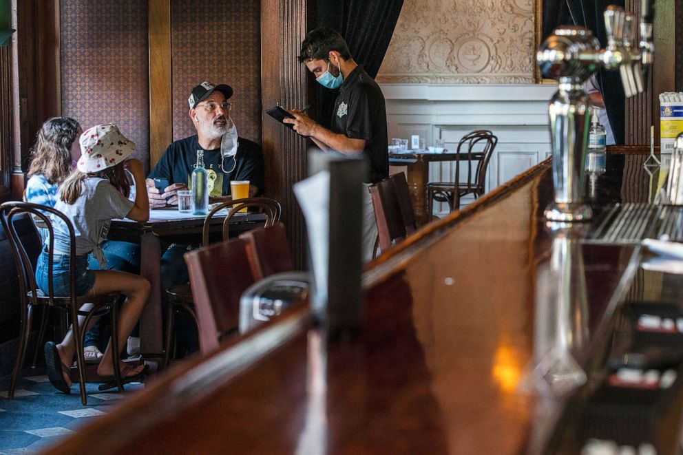 PHOTO: A waiter in a protective face mask takes a customer's order during lunch at a restaurant in Hoboken, N.J., Sept. 4, 2020.