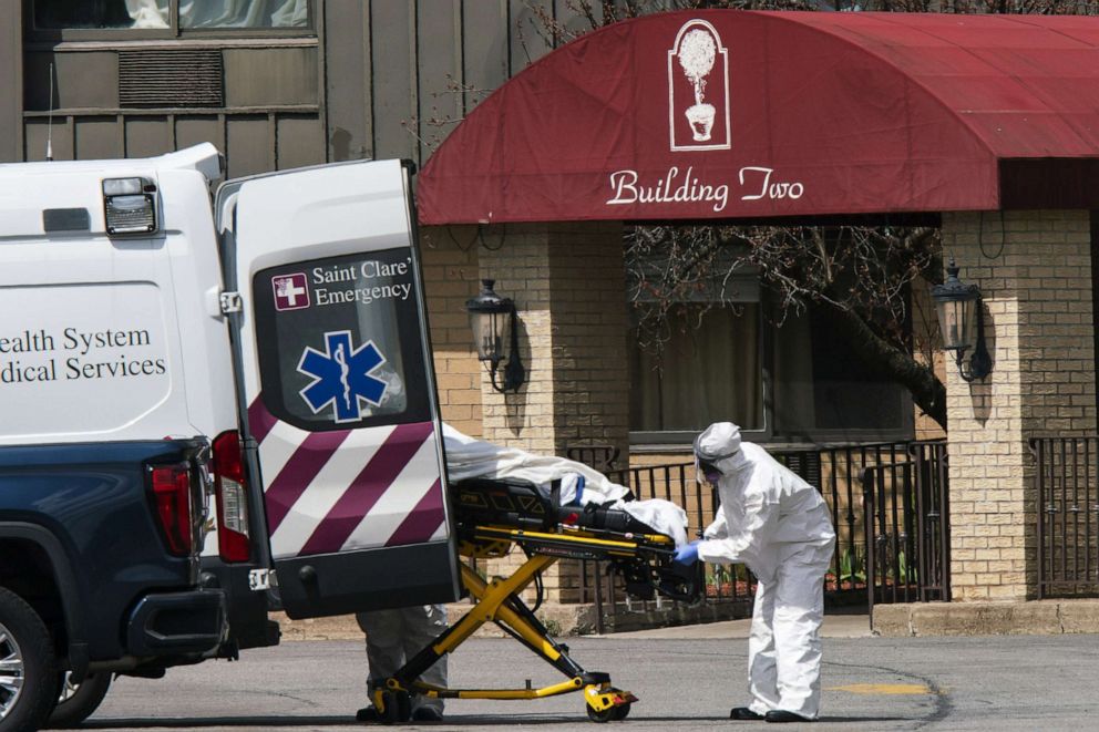 PHOTO: Medical workers load a deceased person into an ambulance while wearing personal protective equipment (PPE) at Andover Subacute and Rehabilitation Center, April 16, 2020 in Andover, N.J. 