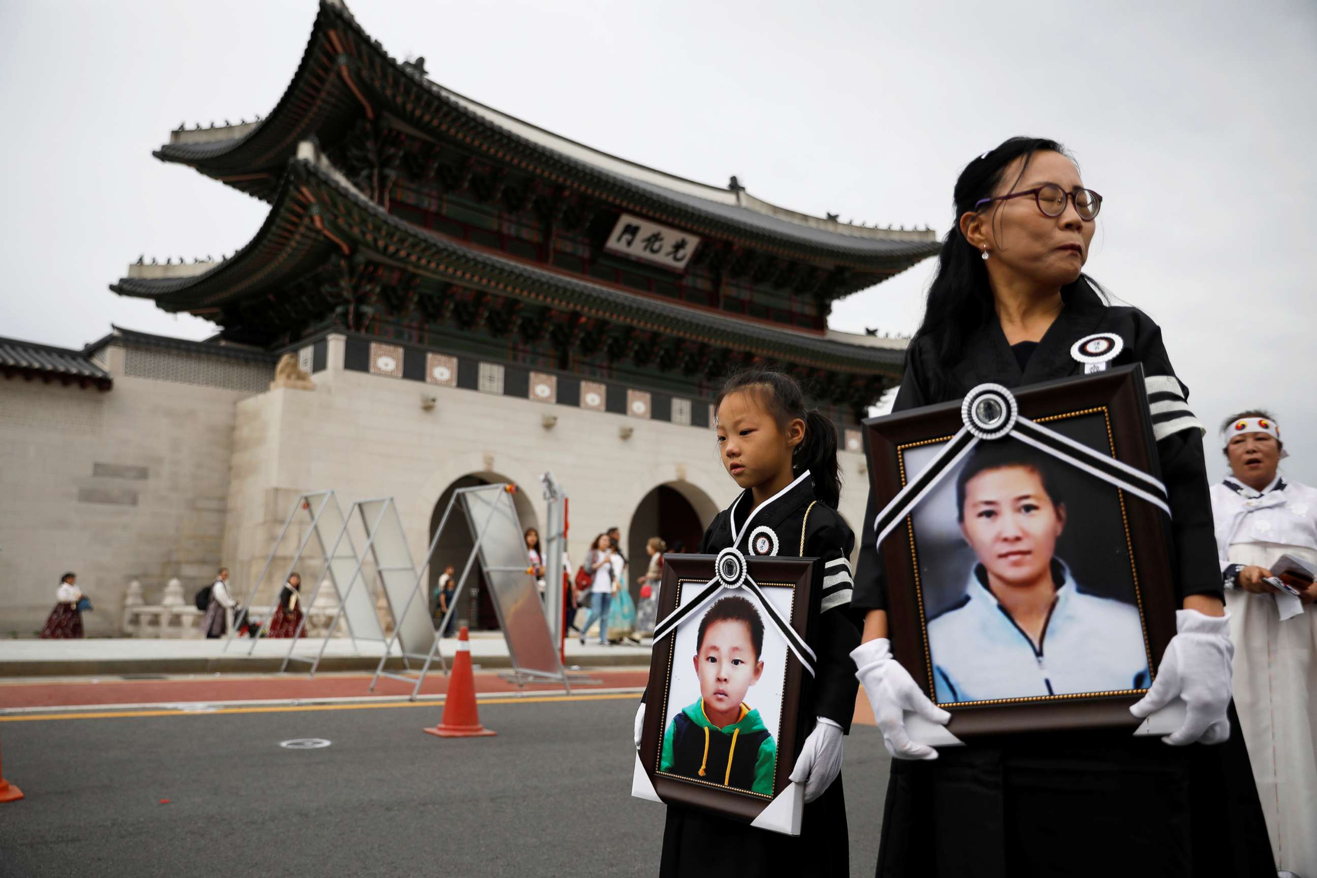 PHOTO: A girl and her North Korean defector mother hold portraits of a 42-year-old defector mother and  her 6-year-old son who were found dead in starvation as they march during their funeral in Seoul, South Korea, Sept. 21, 2019.   