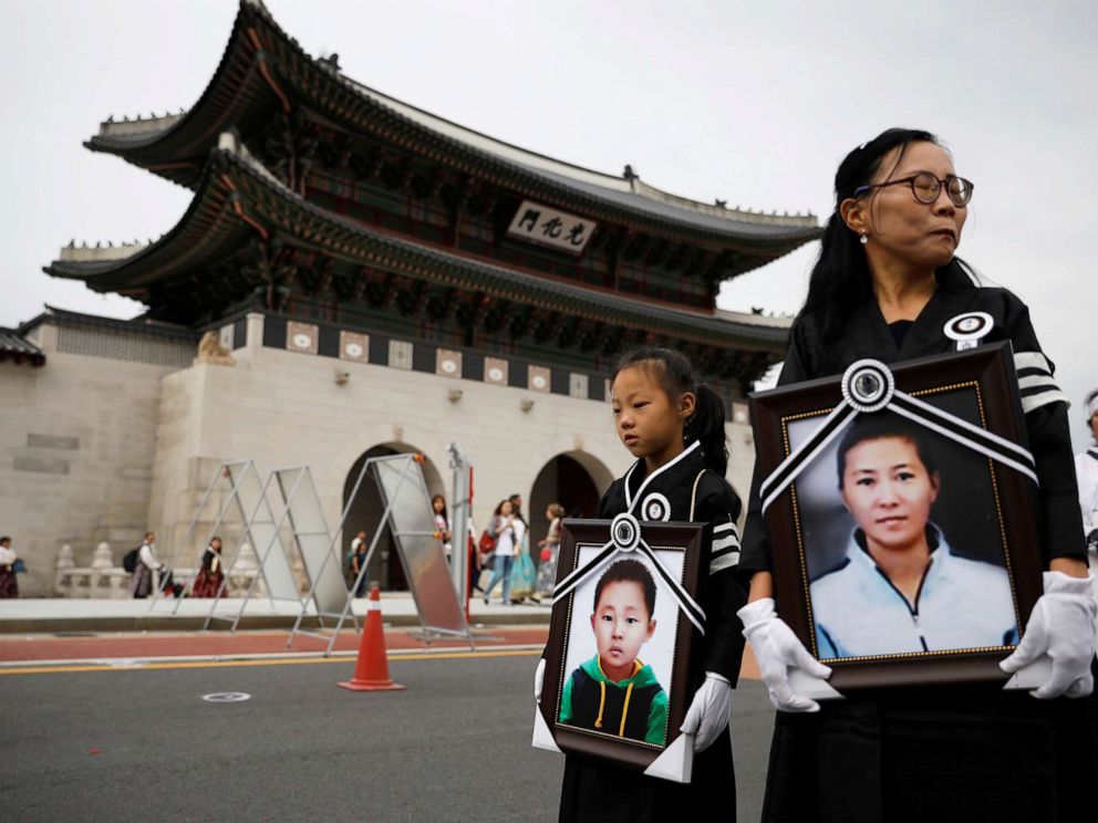 PHOTO: A girl and her North Korean defector mother hold portraits of a 42-year-old defector mother and her 6-year-old son who were found dead in starvation as they march during their funeral in Seoul, South Korea, Sept. 21, 2019.