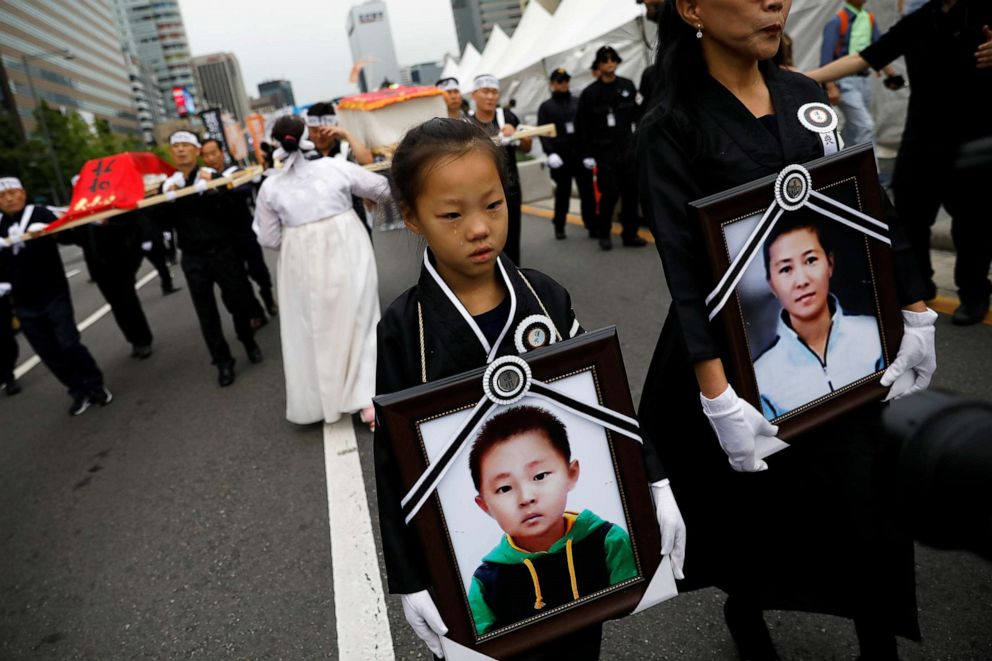 PHOTO: A girl and her North Korean defector mother hold portraits of a 42-year-old defector mother and  her 6-year-old son who were found dead of starvation in Seoul, South Korea, Sept. 21, 2019.    