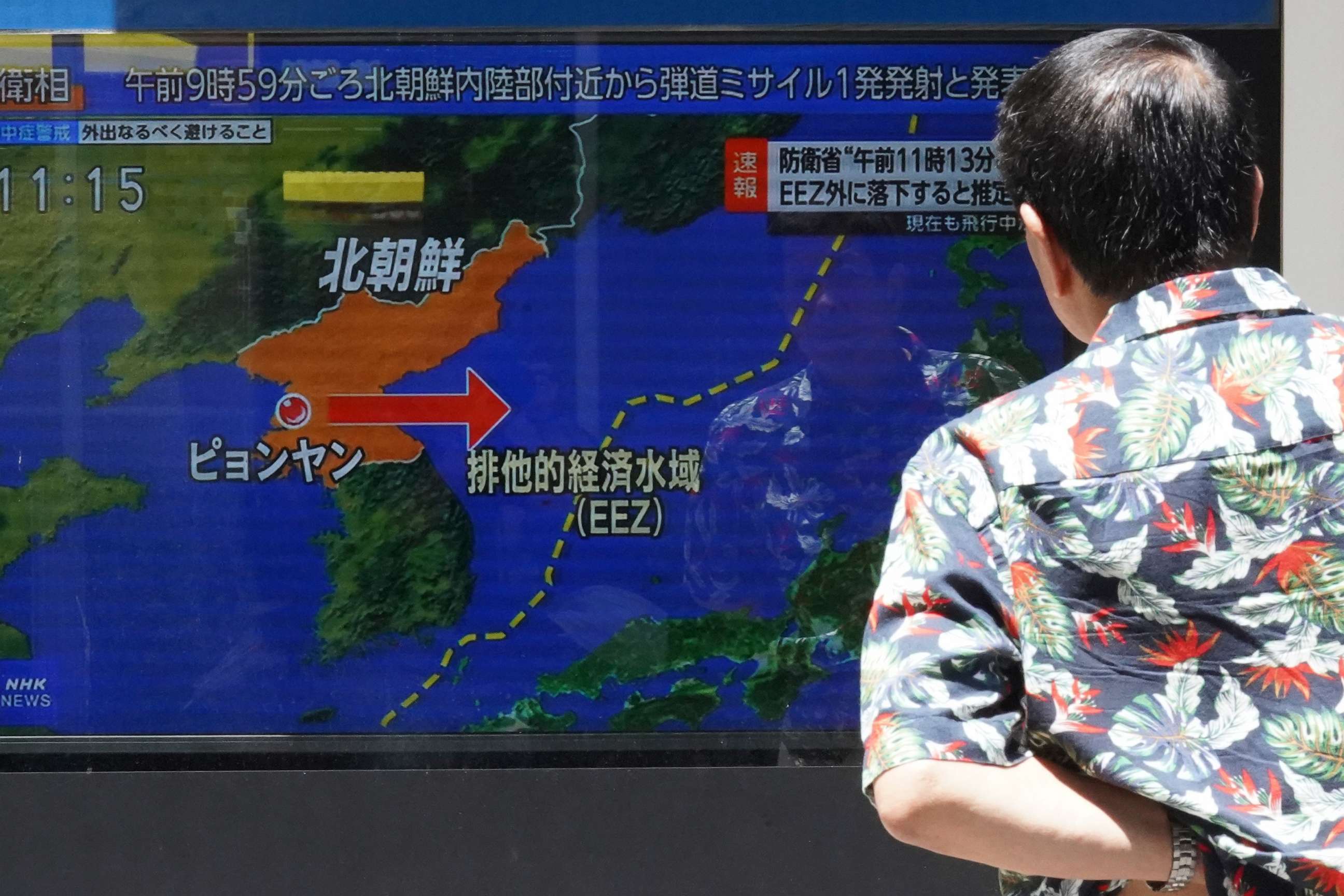 PHOTO: A man stands along a sidewalk to watch a TV showing a news program on North Korea's missile launch Wednesday, July 12, 2023, in Tokyo.