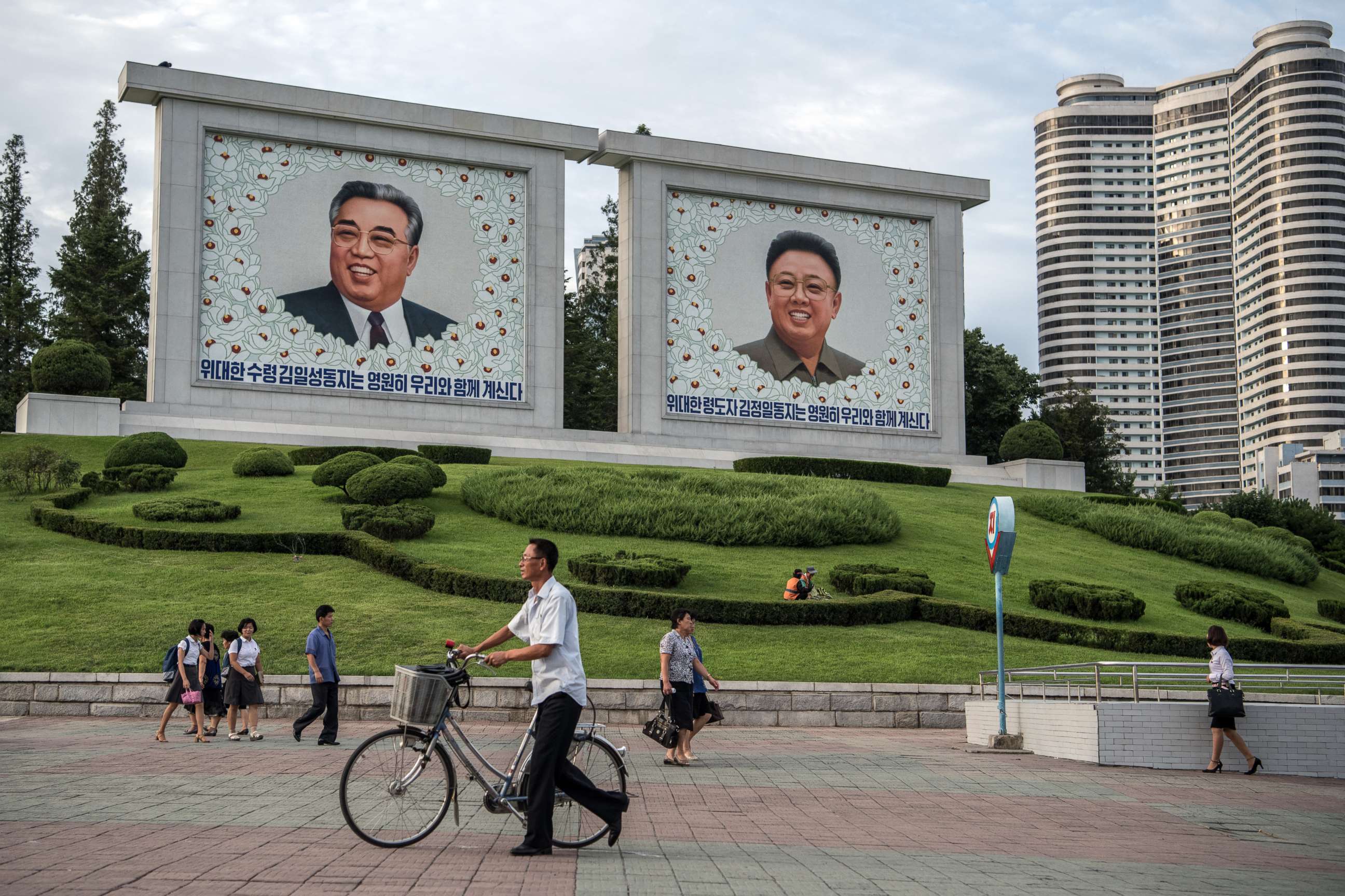 PHOTO: People walk past pictures of Kim Il-sung and Kim Jong-il on Aug. 18, 2018 in Pyongyang, North Korea.