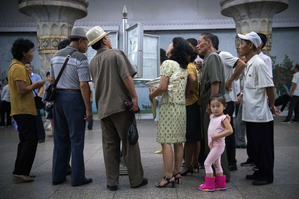 PHOTO: A little girl looks back away as people read a newspaper displayed in a station on the Pyongyang metro on Aug. 21, 2018 in Pyongyang, North Korea.