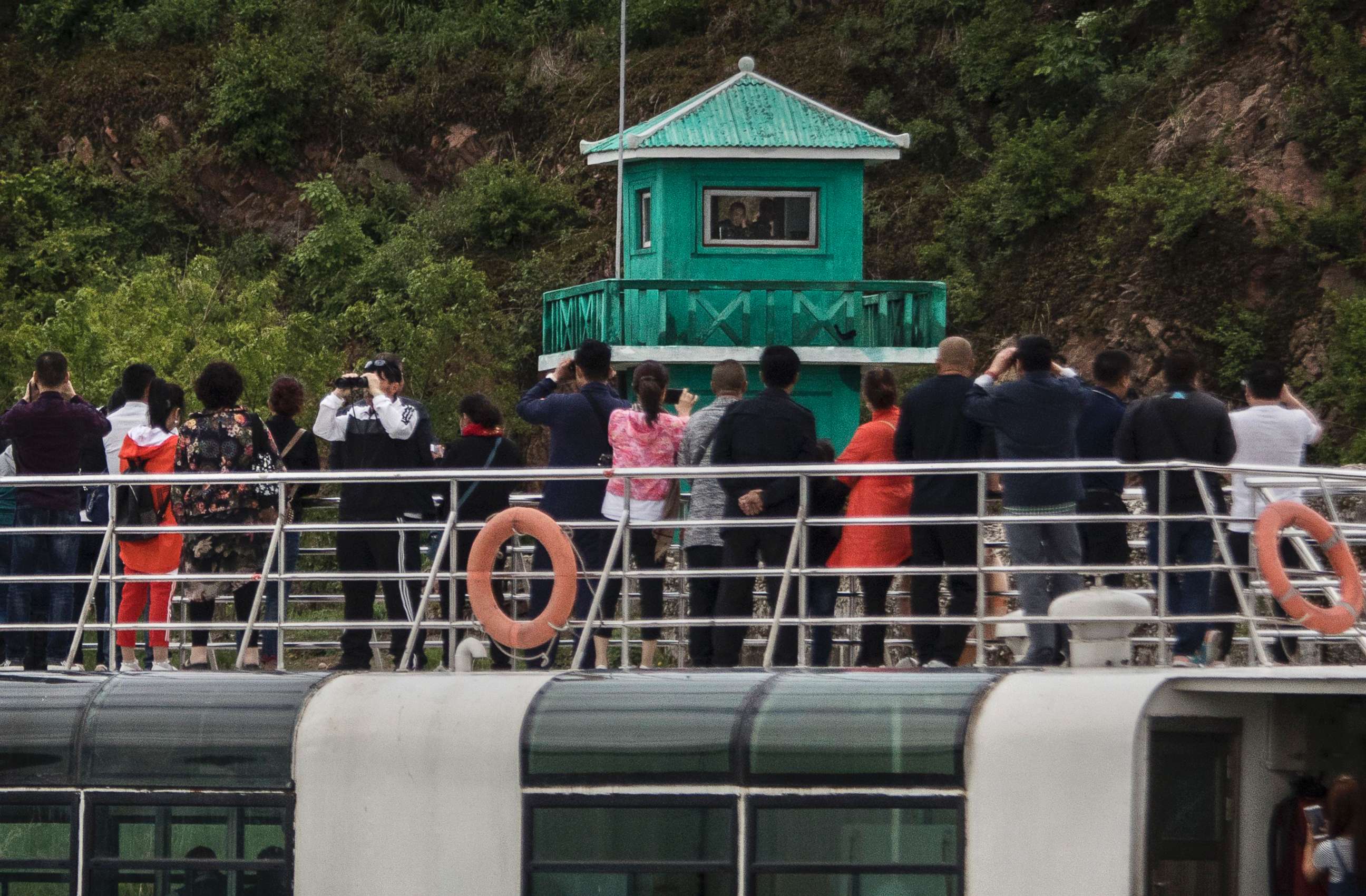 PHOTO: Chinese tourists aboard a sight-seeing boat take pictures of a North Korean soldier in a watchtower along the Yalu river north of the border city of Dandong, China and Sinuiju, North Korea, May 23, 2017. 