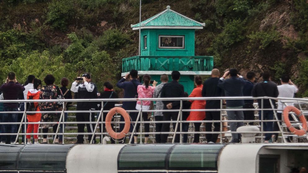 PHOTO: Chinese tourists aboard a sight-seeing boat take pictures of a North Korean soldier in a watchtower along the Yalu river north of the border city of Dandong, China and Sinuiju, North Korea, May 23, 2017. 
