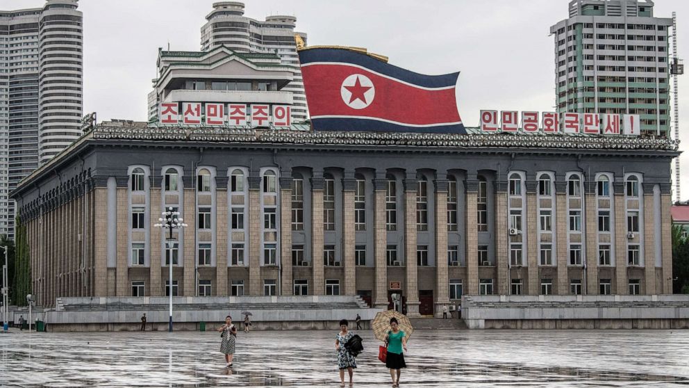 Women walk across Kim Il-sung Square as a huge North Korea flag is displayed atop the Central Committee of the Workers' Party of Korea building, Aug. 23, 2018, in Pyongyang, North Korea.