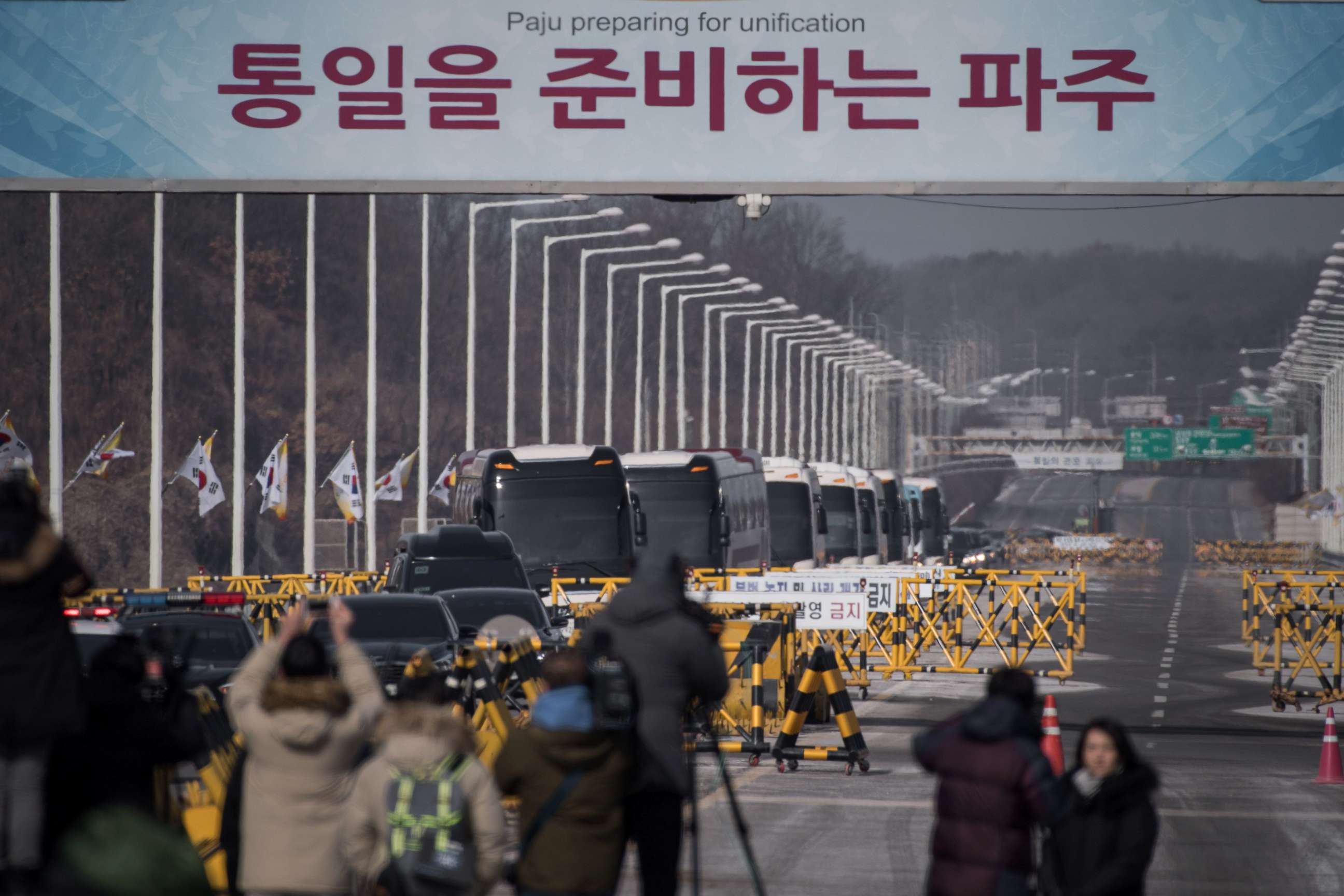 PHOTO: Busses carrying a 280-member delegation of North Korean cheerleaders crosses a checkpoint on Tongil bridge after arriving in South Korea, in Paju on February 7, 2018. 