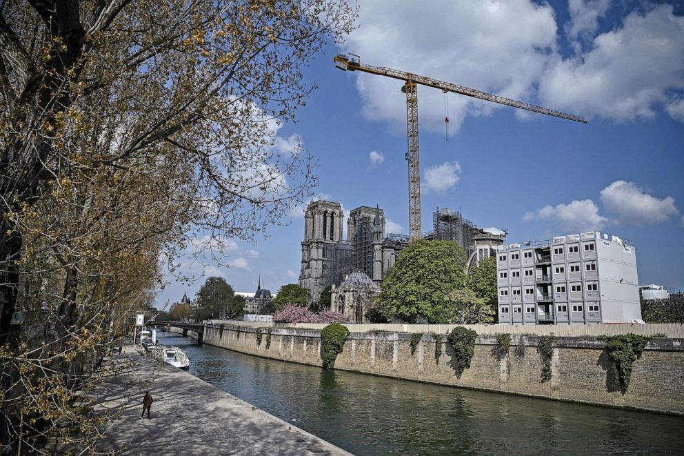 PHOTO: A man walks by the Seine river, near Notre-Dame de Paris cathedral, on April 14, 2021 in Paris.