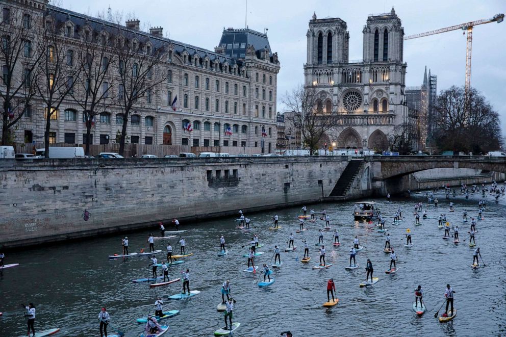 PHOTO: Competitors steer their Stand Up Paddle boards past Notre Dame cathedral during a race on the Seine river in Paris, Sunday, Dec. 5, 2021.