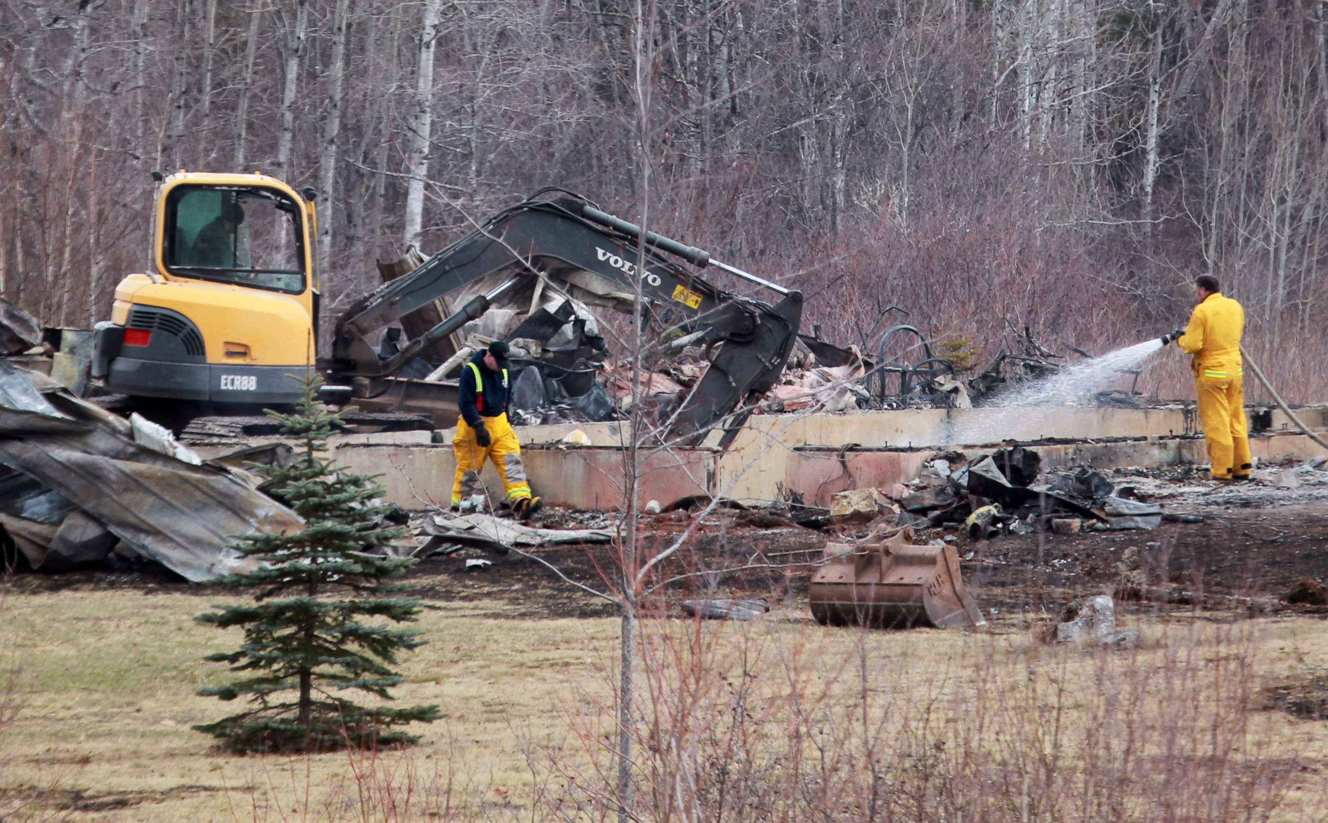 PHOTO: Wentworth volunteer firefighters douse hotspots as an excavator digs through the rubble of a destroyed home linked to Sunday's deadly shooting rampage on April 20, 2020 in Wentworth Centre, Nova Scotia, Canada. 
