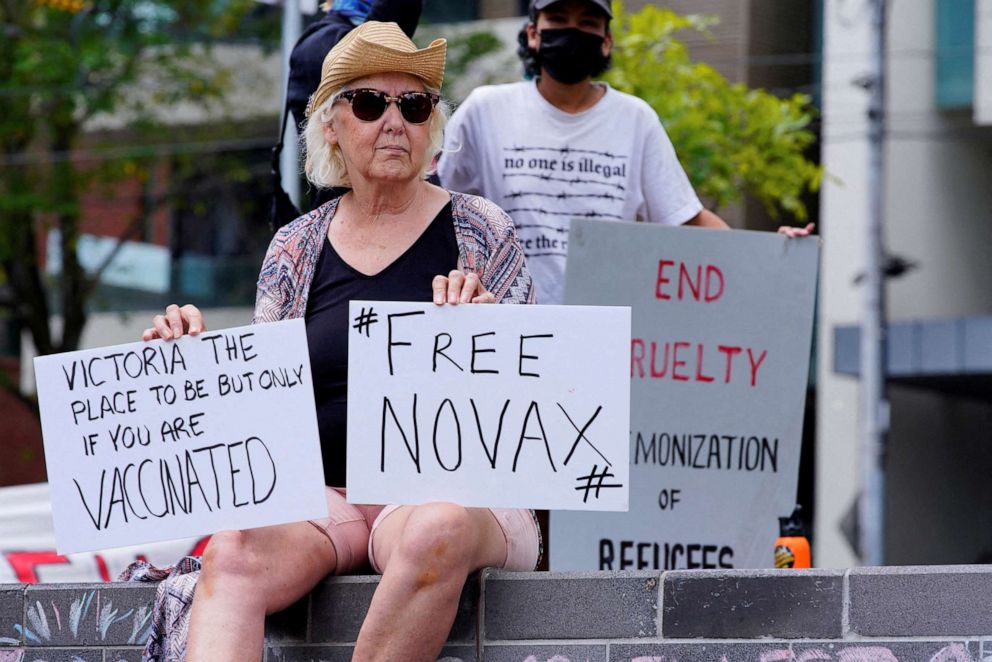 PHOTO: A protestor holds signs outside the Park Hotel, where Serbian tennis player Novak Djokovic is believed to be held, in Melbourne, Australia, Jan. 6, 2022.