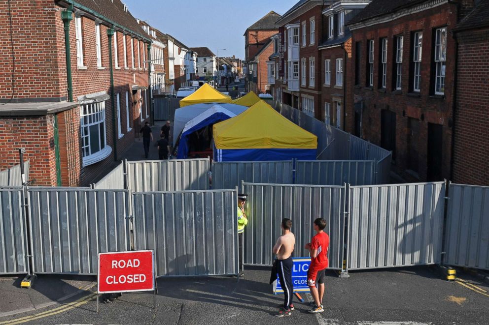 PHOTO: Work goes on behind the barriers across Rollestone Street, outside the John Baker House Sanctuary Supported Living in Amesbury, southern England, July 5, 2018, in connection with the investigation after a man and woman were found unconscious.