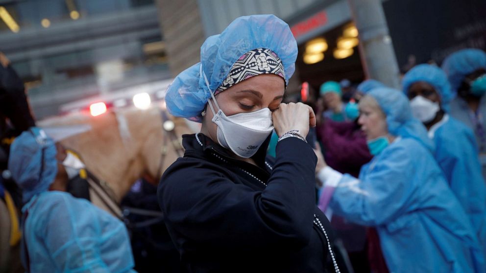 PHOTO: A nurse wipes away tears as she stands outside NYU Langone Medical Center in Manhattan as New York Police Department (NYPD) Mounted Police and other units came to cheer and thank healthcare workers at 7pm, April 16, 2020.