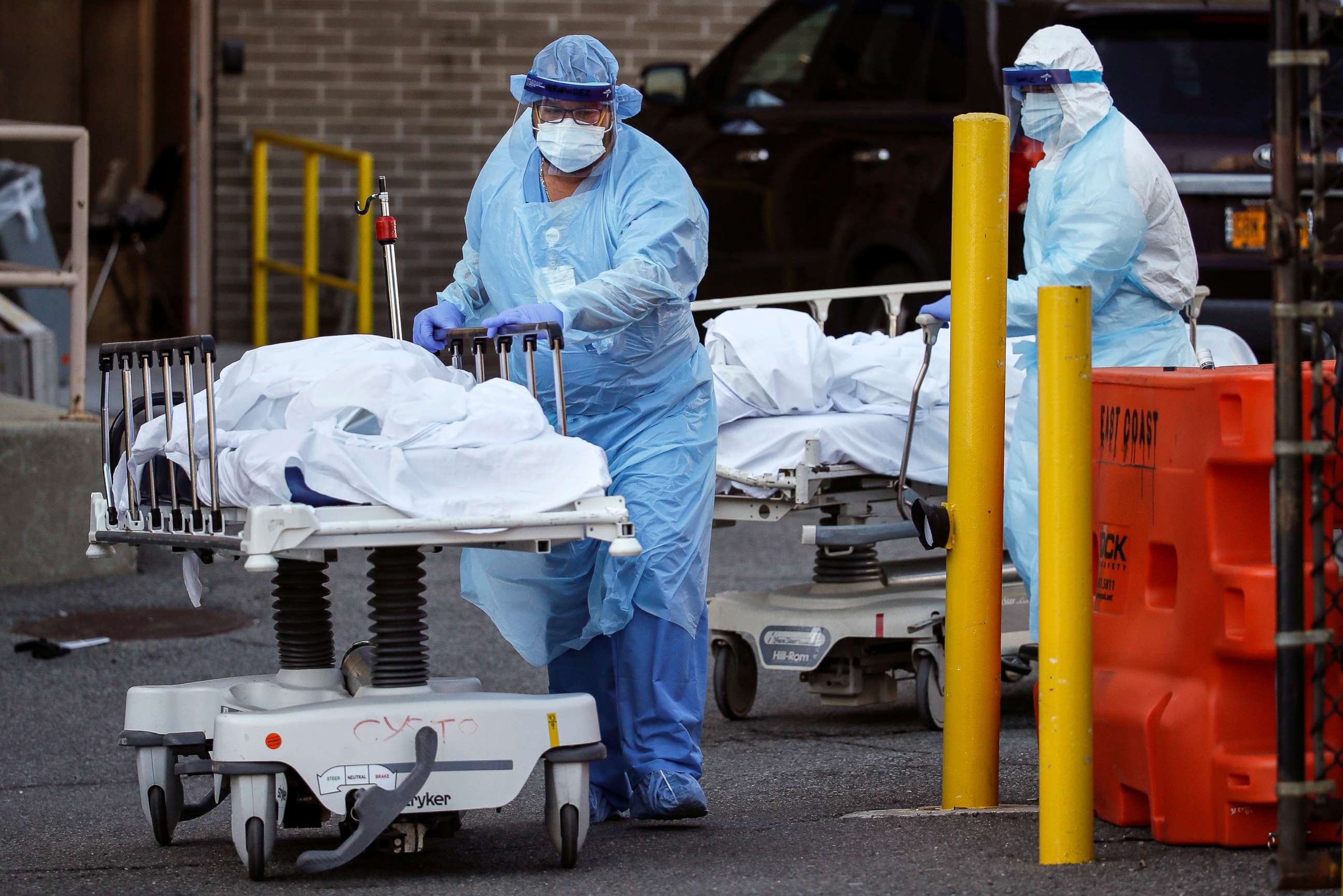 PHOTO: Medical workers wearing personal protective equipment wheel bodies to a refrigerated trailer serving as a makeshift morgue at Wyckoff Heights Medical Center, April 6, 2020, in the Brooklyn borough of New York.