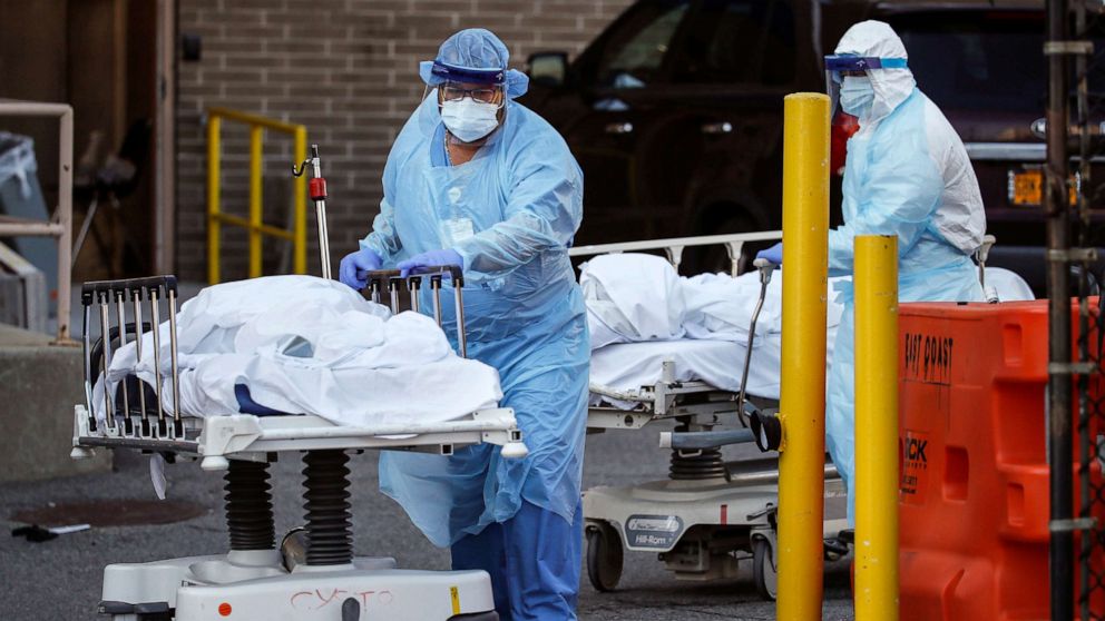PHOTO: Medical workers wearing personal protective equipment wheel bodies to a refrigerated trailer serving as a makeshift morgue at Wyckoff Heights Medical Center, April 6, 2020, in the Brooklyn borough of New York.