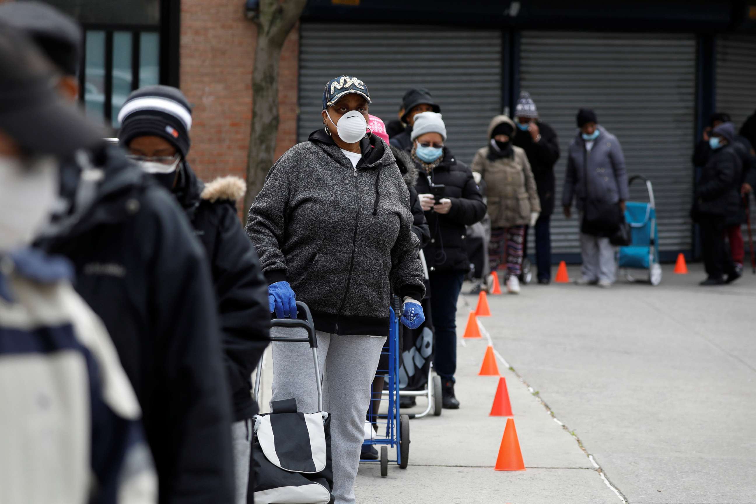 PHOTO: People wearing protective masks wait in line for donated food distribution at the Queensbridge Houses, a public housing complex, during the outbreak of the coronavirus disease (COVID-19) in the Queens borough of New York, April 21, 2020.