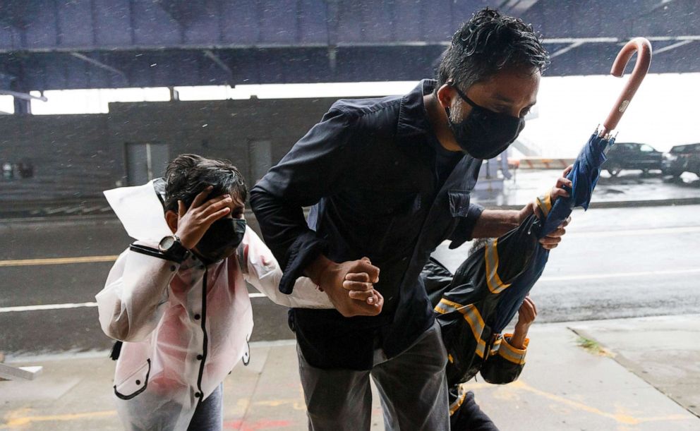 PHOTO: A man and his children try to find shelter from the wind in lower Manhattan as Tropical Storm Isaias passes through New York City, Aug. 4, 2020.