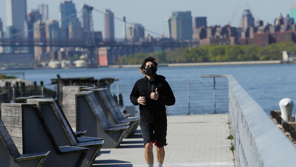 PHOTO: A man, wearing a face mask, runs along the East River during the coronavirus pandemic at Hunters Point Park South, May 14, 2020, in Queens, New York.