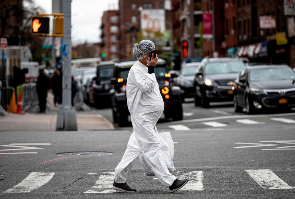 PHOTO: A pregnant woman wearing a protective suit and a mask crosses the streets in the Elmhurst neighborhood of Queens, April 27, 2020 in New York City.