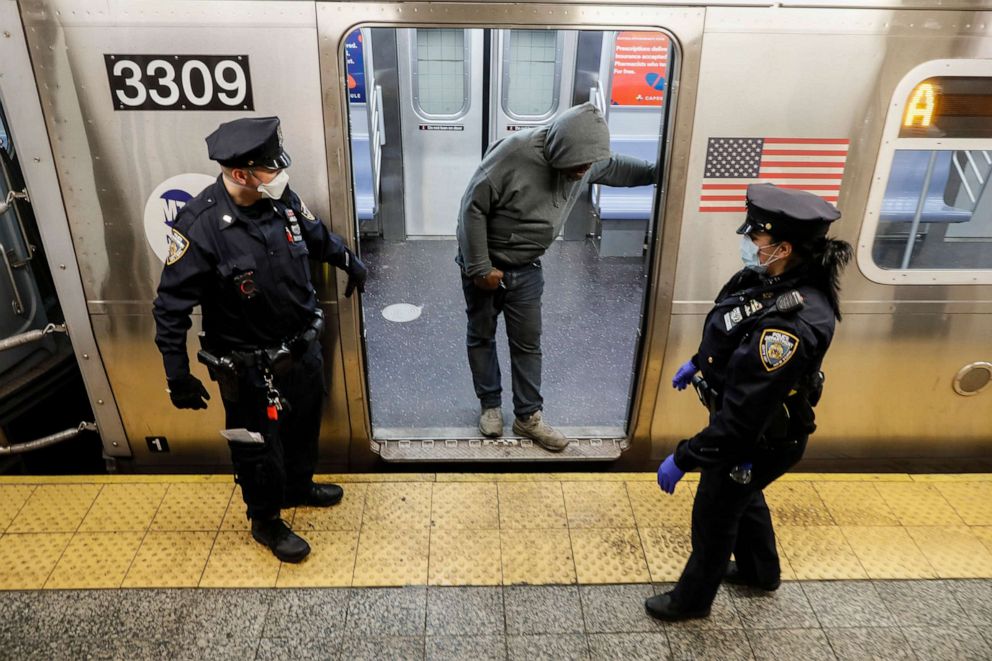 PHOTO: NYPD officers direct passengers to exit the 207th Street A-train station, April 30, 2020, in the Manhattan borough of New York.