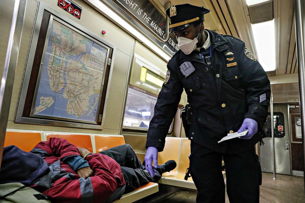 PHOTO: NYPD officers wake up sleeping passengers and direct them to the exits at the 207th Street A-train station, April 30, 2020, in the Manhattan borough of New York.