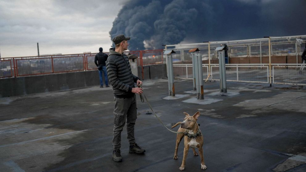 PHOTO: A man stands with his dog as smoke rises after an attack by Russian army in Odessa, on April 3, 2022.