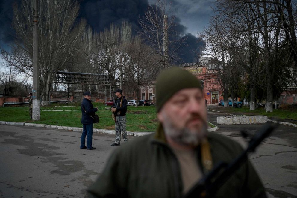 PHOTO: Ukrainian security officers stand as smoke rises after an attack by Russian army  in Odessa, on April 3, 2022.
