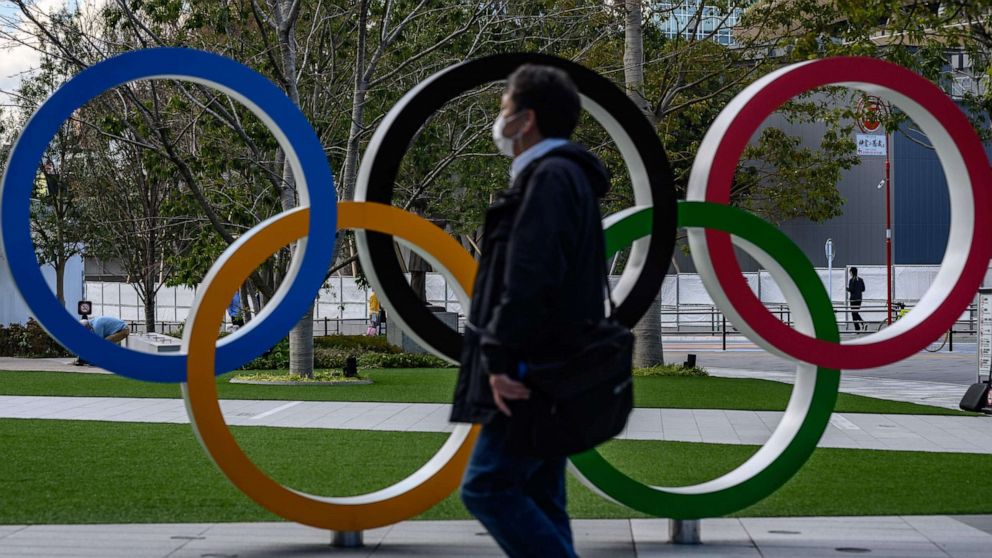 PHOTO: In this file photo taken on March 11, 2020, a man wearing a face mask walks in front of the Olympic Rings in Tokyo, Japan.