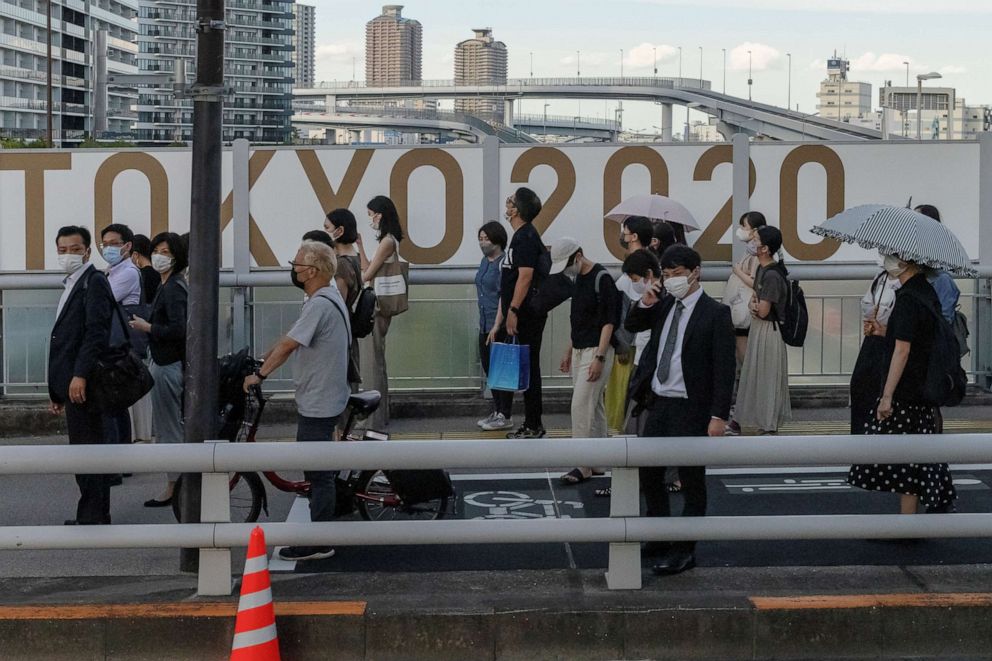 PHOTO: People stand in front of Tokyo 2020 Olympic Games signage as the coronavirus disease outbreak continues in Tokyo, Japan, July 21, 2021.