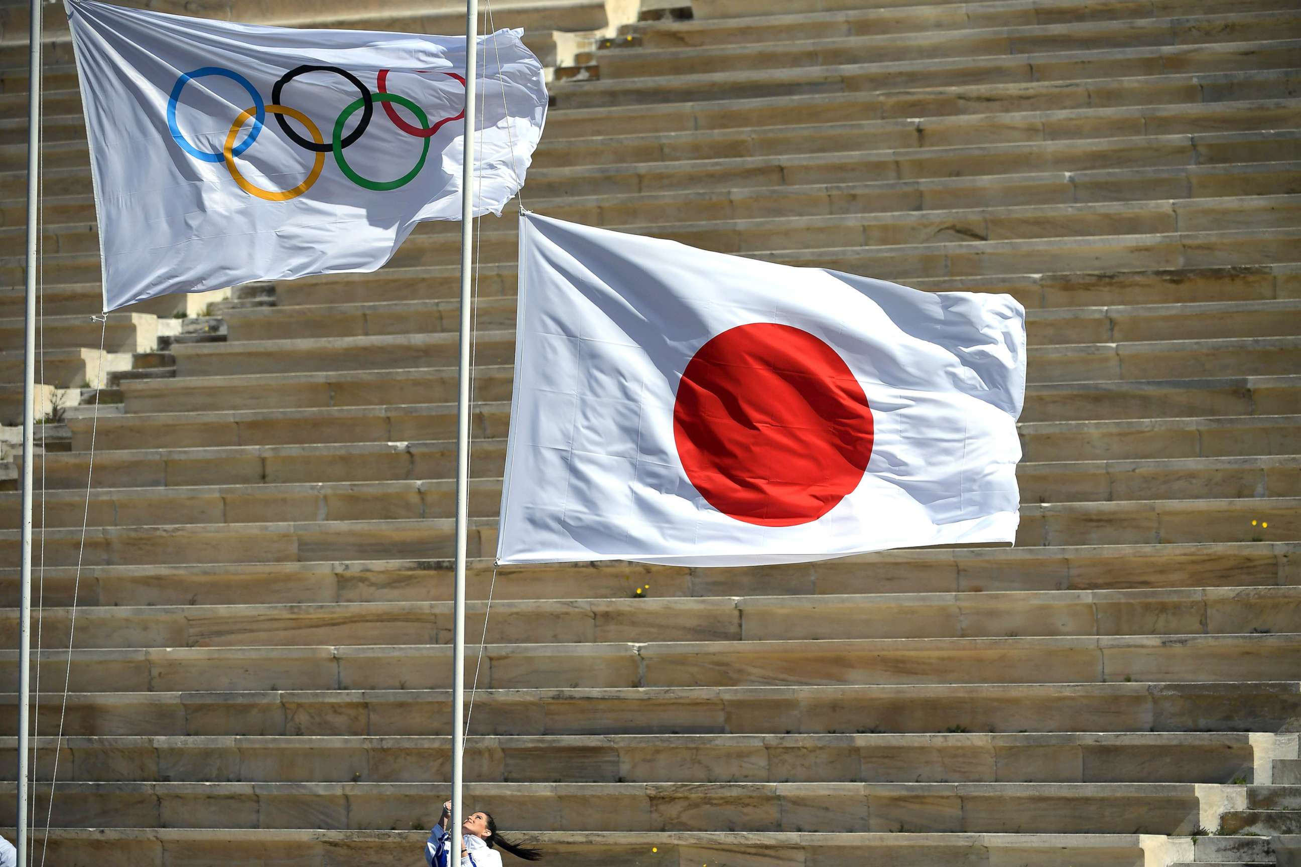 PHOTO: Japan's flag is raised next to the Olympic flag during the olympic flame handover ceremony for the 2020 Tokyo Summer Olympics, March 19, 2020, in Athens. 