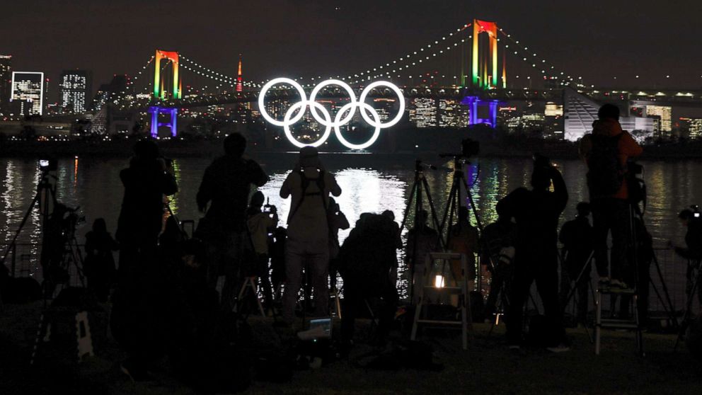 PHOTO: Journalists take images of the illuminated Olympic Rings monument at Odaiba Marine Park as the Rainbow Bridge is illuminated in rainbow colors to mark half a year before the opening of the Tokyo 2020 Olympic Games in Tokyo, Japan, Jan. 24, 2020. 