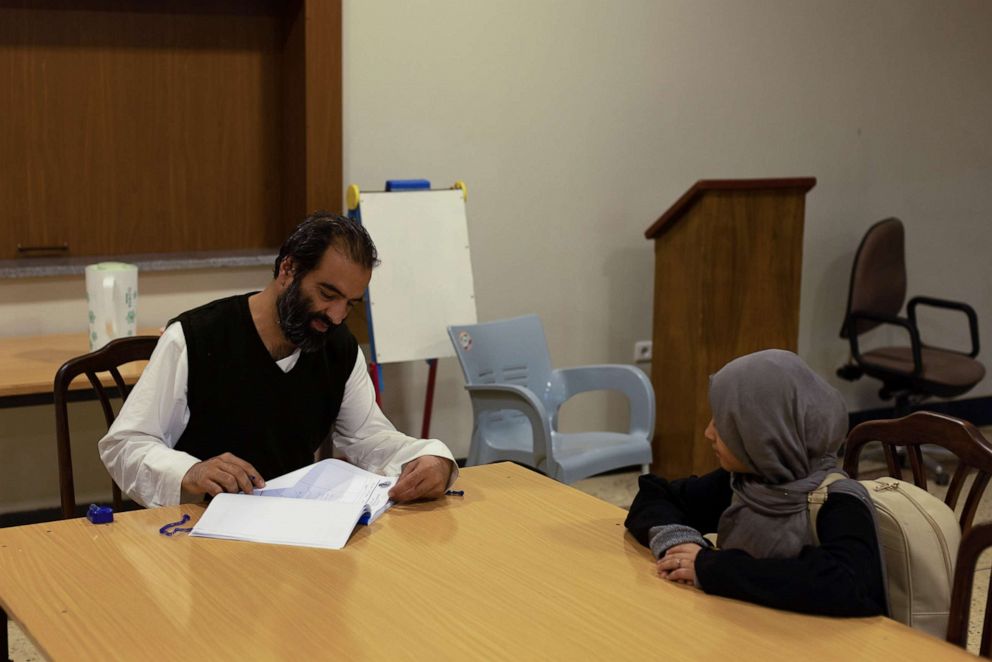 PHOTO: Ahmad Khalil Mayan, 40, the director of the orphanage, reviews school notes with a girl, in Kabul, Afghanistan, Oct. 12, 2021. 