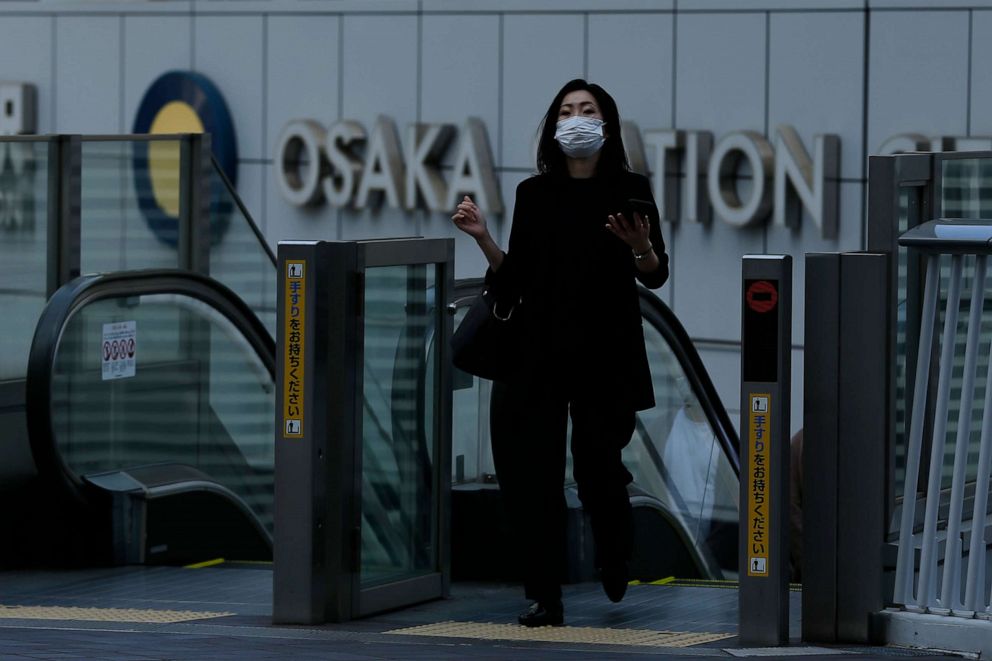 PHOTO: A woman wearing a face mask to protect against COVID-19 walks out of Osaka Station in Osaka, Japan, on April 23, 2021.