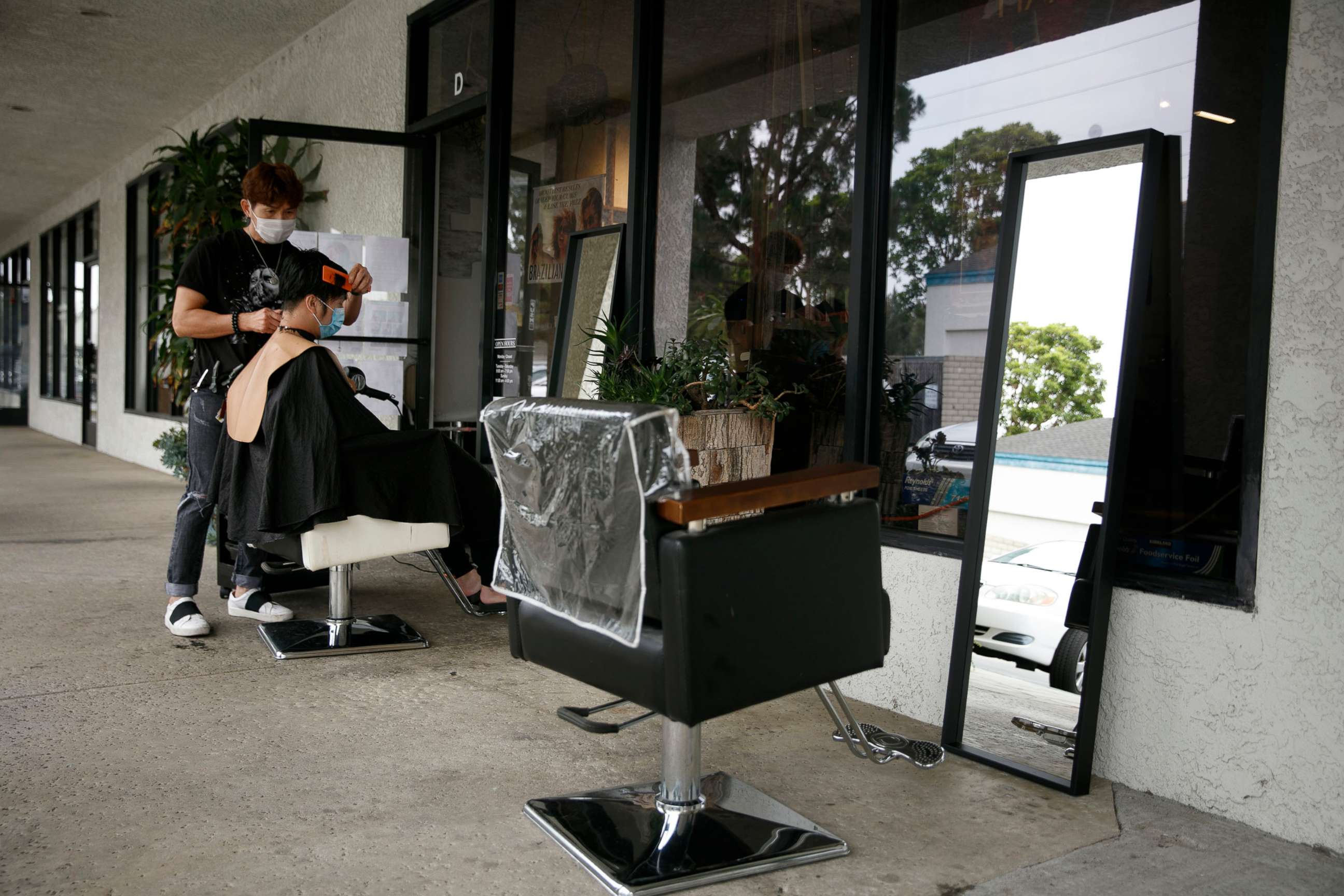 PHOTO: Hairstylist Travis Vu gives a haircut to Minh Dao at his outdoor hair salon in Fountain Valley, Calif., July 22, 2020.