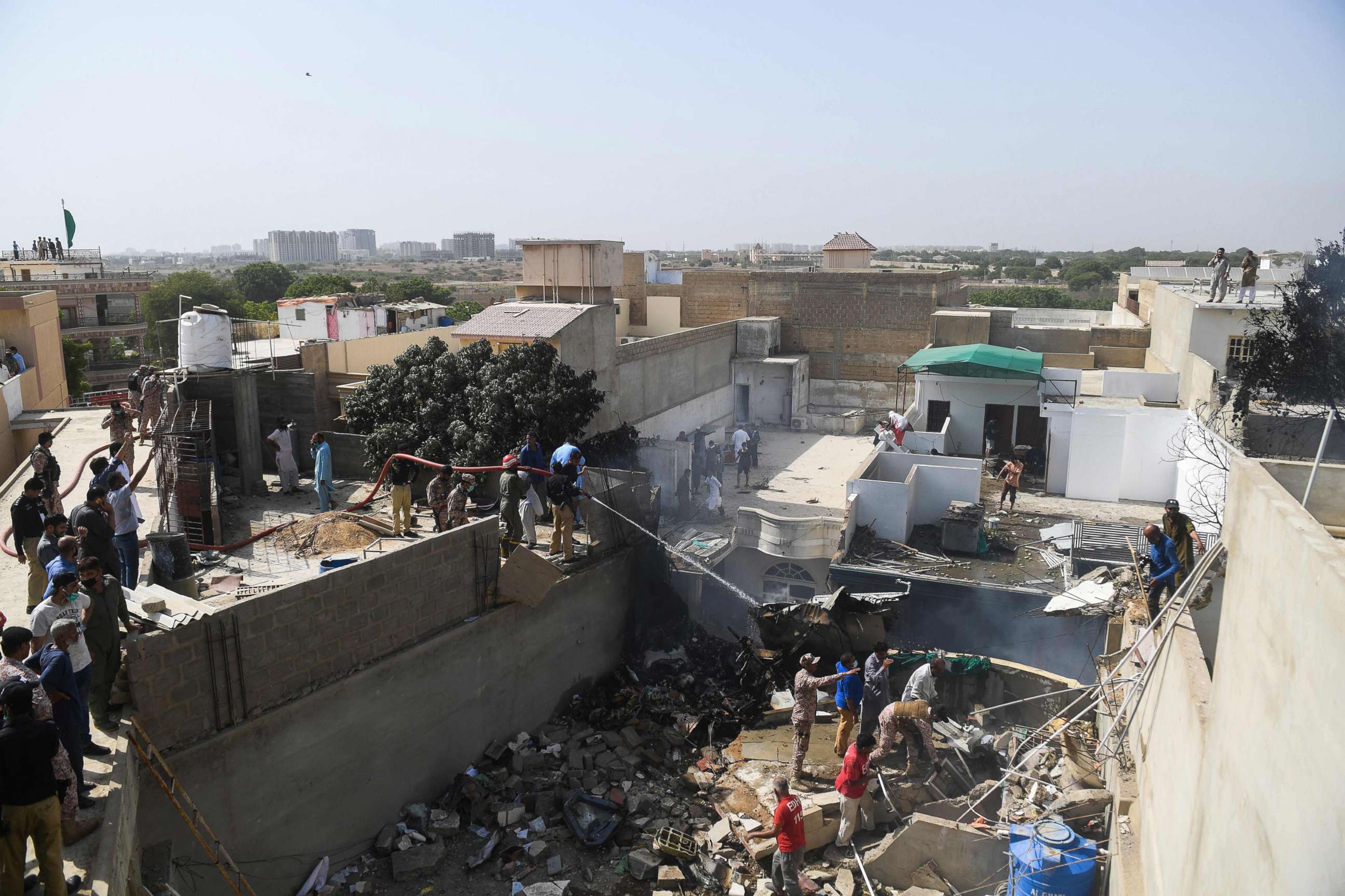 PHOTO: Rescue workers spray water on the part of a Pakistan International Airlines aircraft after it crashed at a  residential area in Karachi on May 22, 2020.