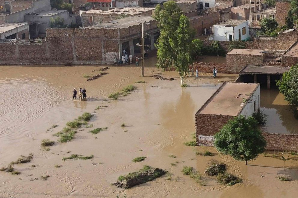 PHOTO: Residents wade through a flood hit area following heavy monsoon rains in Charsadda district of Khyber Pakhtunkhwa, Aug. 29, 2022.
