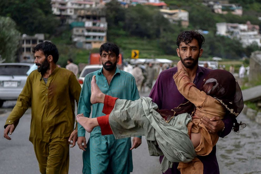 PHOTO: A man carries his sick daughter along a road damaged by flood waters following heavy monsoon rains in Madian area in Pakistan's northern Swat Valley, Aug. 27, 2022.